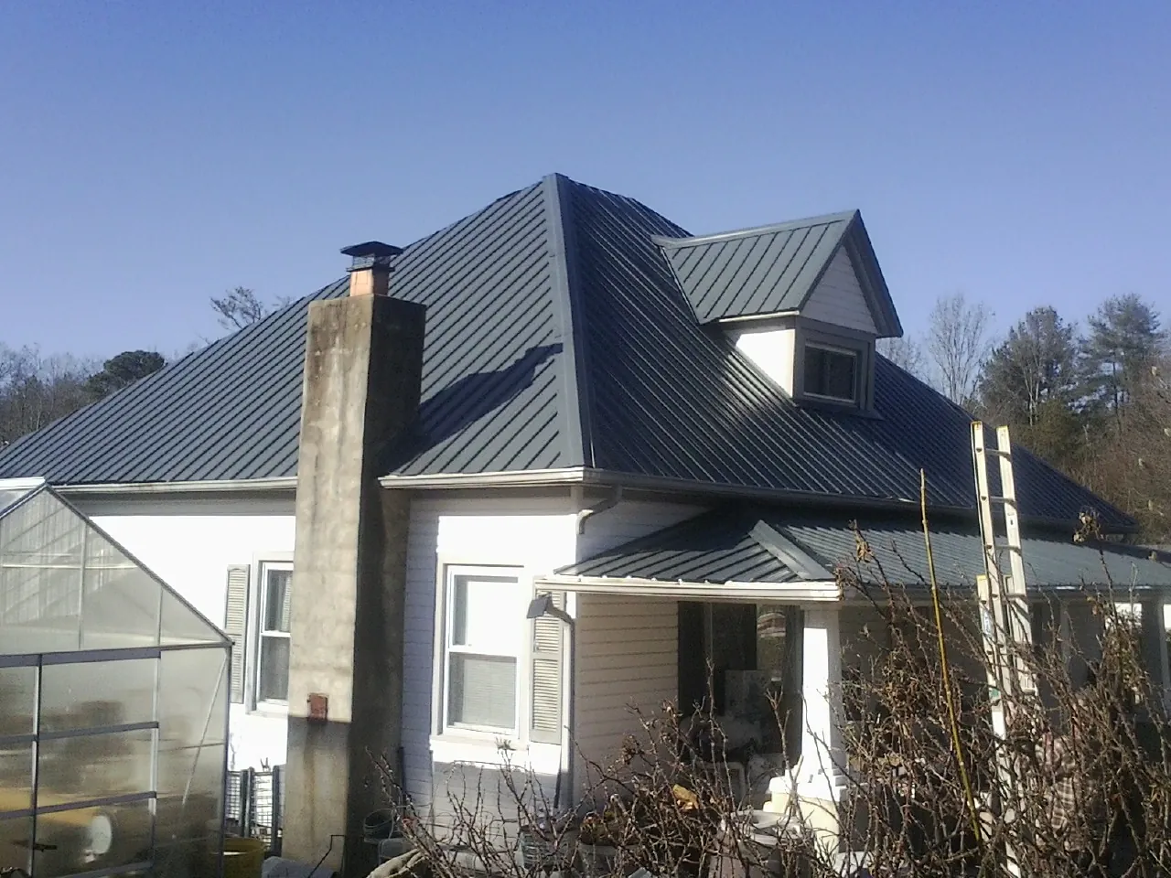 Dark blue standing seam metal roof on a white farmhouse with dormer — Slate & Tile Roof Repair by Roofing Brothers in Summersville