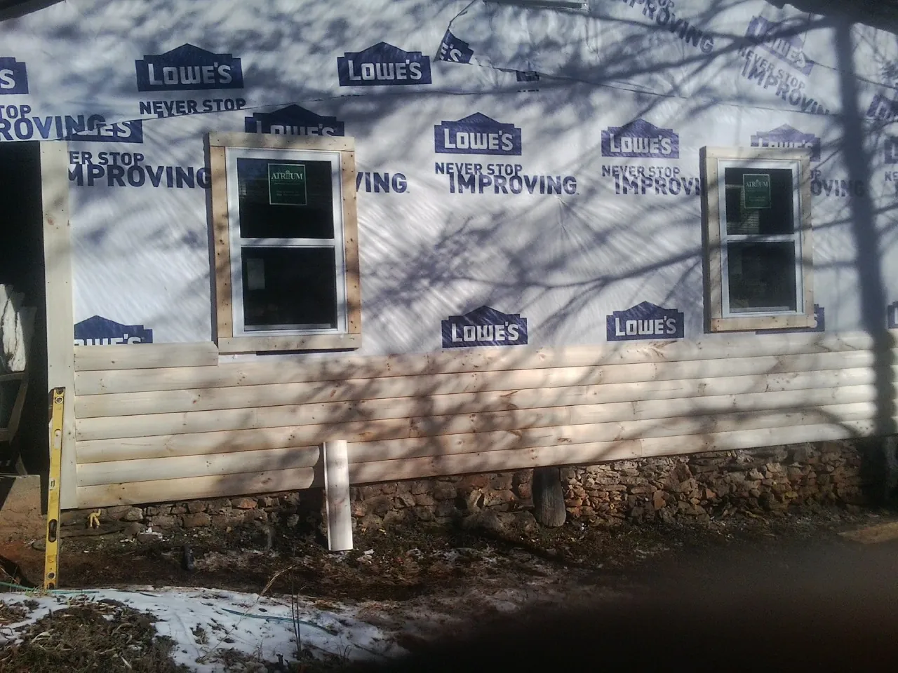 House wrap and new log siding going up on an exterior wall in Summersville
