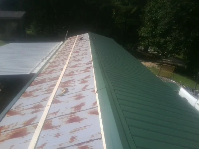 Old rusted panels beside newly installed green metal roofing — Wind Damage Roof Repair by Roofing Brothers in Summersville